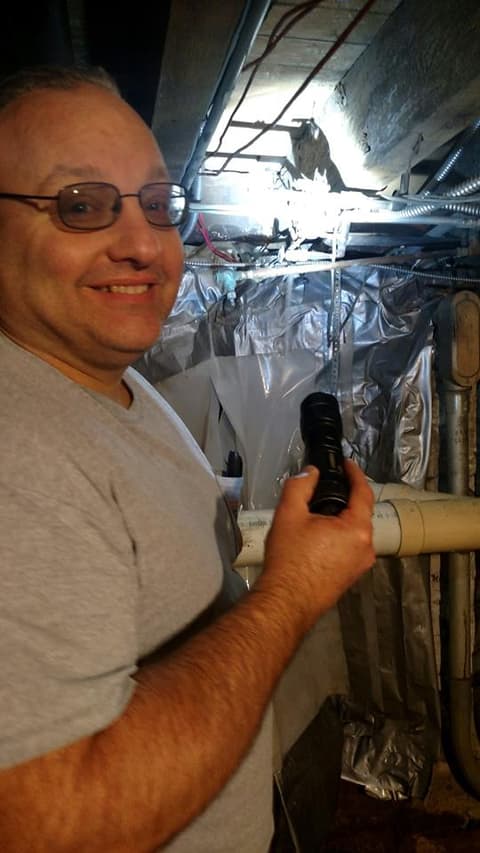 Plumber with flashlight in basement mechanical area